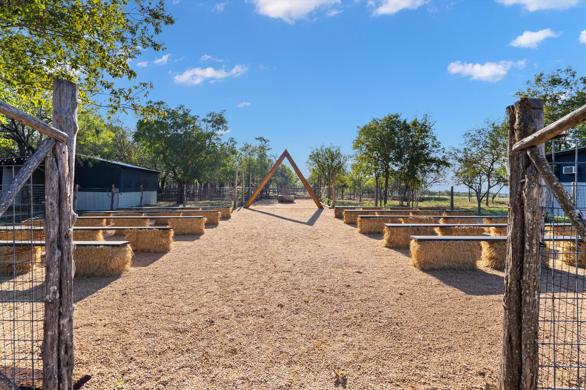 Ceremony aisle with hay-bale benches and a timber arch
